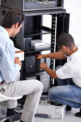 Finding the problem and fixing it. Two IT professionals working on a server.