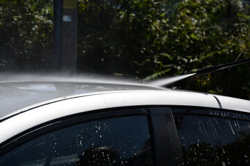 Fototapeta na wymiar Washing a silver car with pressure washer suds and a cloth 