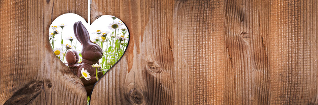Easter chocolate bunny rabbit with daisies behind wooden planks panoramic background with a heart