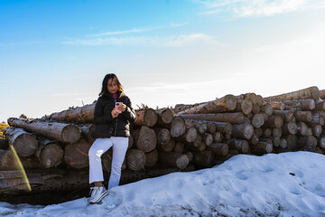 middle aged woman wearing winter clothes using smart phone in the snow over a mountain