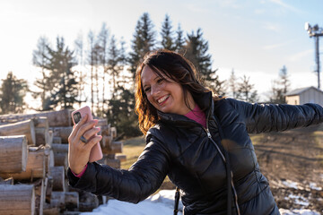 middle aged woman wearing winter clothes taking a selfie over a mountain