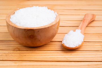 Sea salt in a bowl on a wooden background, sea salt is the salt produced by the evaporation of seawater.