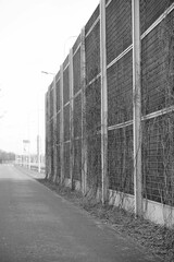 Grayscale vertical shot of a sound barrier wall in an empty street