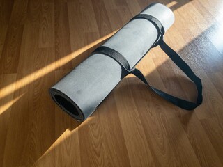 An exercise mat rolled up  on a wooden floor