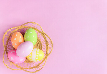 Fototapeta na wymiar Happy Easter holiday greeting card concept. Colorful Easter Eggs and spring flowers on pastel pink background. Flat lay, top view, copy space.