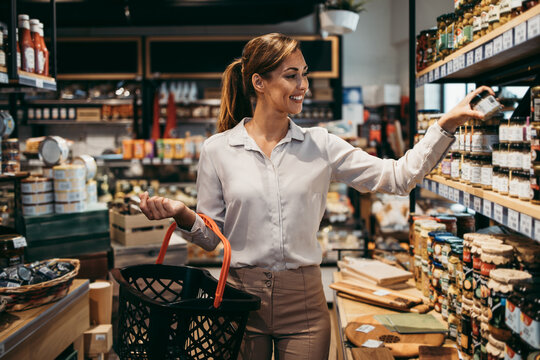 Beautiful young and elegant woman buying some healthy food and drink in modern supermarket or grocery store. Lifestyle and consumerism concept.