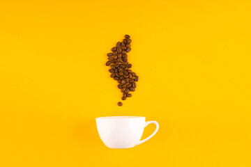 White coffee cup with beans in shape of coffee steam. Yellow background. Copy space