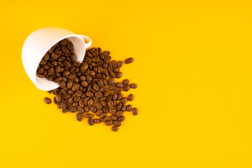 white coffee cup with beans. Yellow background. Copy space