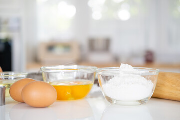 Fresh ingredients for delicious homemade cake on white  table and kitchen background. ingredients and tools to make a cake, flour, butter,eggs