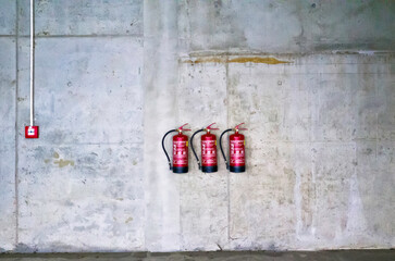 grey industrial wall with red fire extinguishers 