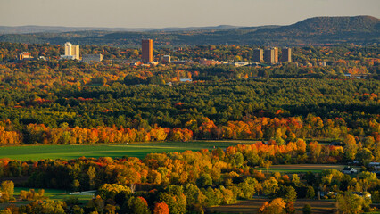 Fall foliage with the Greater Amherst, Massachusetts urban landscape in the distance - obrazy, fototapety, plakaty