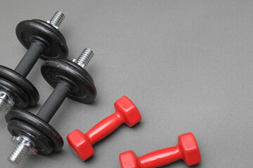 Fitness background. Dumbbells on a gray mat. Sports concept - gray mat, two black dumbbells 10 kg