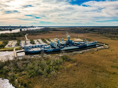 The Navy Ship Is Parked At A Dock With A Large Building In The Background