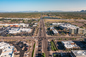 Scottsdale, Arizona USA - October 1 2021: Aerial view of commercial and residential buildings along road with landscape in the distance 