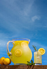 Closeup of a tasty lemon juice in a glass with lemon slices against a blue sky