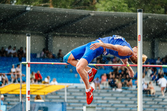 male athlete jumper high jump in rain, athletics competition, Mizuno spikes shoes for jumping, sports photos