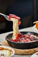 Vertical closeup of a chef cutting a Chicago-style pizza in a pan