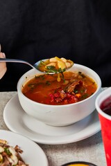 Vertical closeup of a person tasting a soup with beans