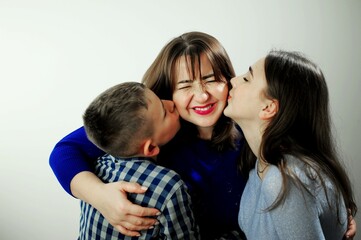 Happy family children kiss mom from two sides. Sons show freedom love Loving family portrait Children from 2 sides kisses mom