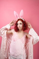 Lovely beautiful young woman posing in sensual pink lingerie and bunny ears. pink background. Studio shot.
