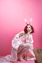 Lovely beautiful young woman posing in sensual pink lingerie and bunny ears. pink background. Studio shot.