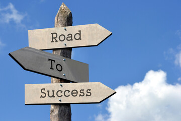 Road to success - wooden signpost with three arrows, sky with clouds