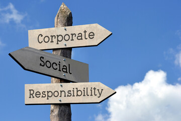 Corporate, social, responsibility - wooden signpost with three arrows, sky with clouds