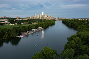 Fototapeta na wymiar Austin, Texas skyline and cityscape with Lady Bird Lake and stand up paddleboard on the river water during golden hour sunset