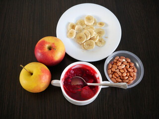 Banana,  fruit jelly, milk dessert with low calories, apples in plates on dark wooden background, healthy breakfast, anti cholesterol diet