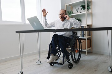 A man in a wheelchair a businessman with tattoos in the office works, talking on the phone, anger and aggression, integration into society, the concept of working a person with disabilities