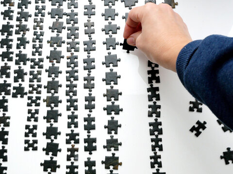 Hand Holding One Puzzle On Many Sorting By Color And Shape Background, Method For Collecting Puzzles