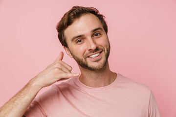 Positive man making call gesture isolated over pink wall