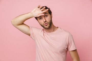 Tired man wiping sweat from his forehead isolated over pink background