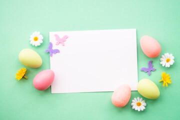 Fototapeta na wymiar Easter greeting card with eggs, flowers and butterflies at color background. Flat lay image with copy space.