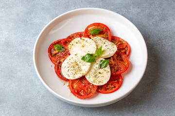 Italian caprese salad with sliced tomatoes, mozzarella, basil, olive oil
