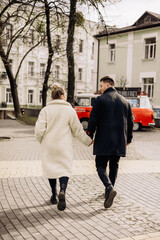 A young couple in love is walking on the street and enjoying the fresh air. Happy married couple. A stylish couple, a man and a woman