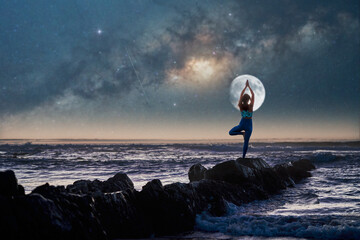 silhouette of a woman in yoga pose on rocks on the beach at night with the moon and milky way in the background	 - obrazy, fototapety, plakaty