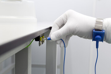 Bracelet on the hand of a man wearing ESD cloth and glove static resistance ESD bracelet or ground equipment, anti-static, used to safely ground is working. Semiconductor manufacturing.