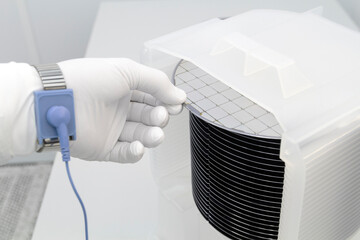 Gloved Hand Holding a Silicon Wafer in plastic holder box used in electronics for the fabrication of integrated circuits. Silicon wafer inspection.