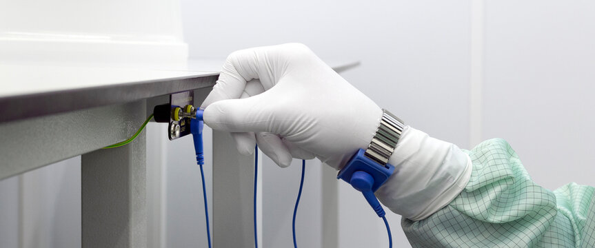 Bracelet on the hand of a man wearing ESD cloth and glove static resistance ESD bracelet or ground equipment, anti-static, used to safely ground is working. Semiconductor manufacturing.Banner
