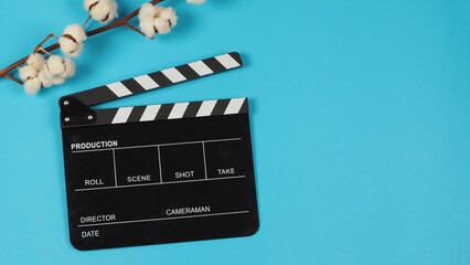 Black clapper board and cotton flowers on blue background.
