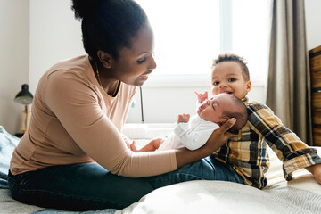 A Portrait of a beautiful black mother, with her nursing baby and child boy