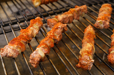 Fried meat with onions on a skewer lies on the grate. Polish street food