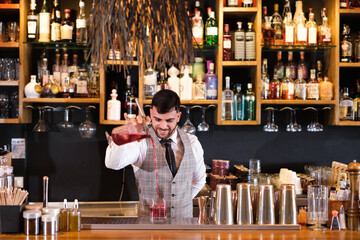 Young bartender making cocktails for his clients to enjoy very tasty drinks. Concept: consumption, alcohol, bartender