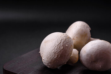Fototapeta na wymiar Fresh raw champignon mushrooms on a wooden cutting board with spices