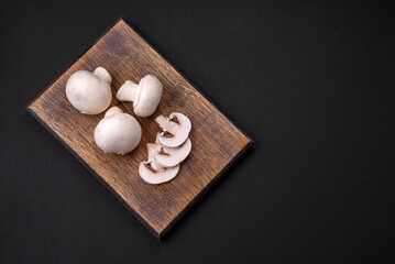 Fresh raw champignon mushrooms on a wooden cutting board with spices