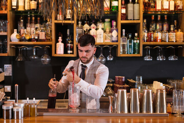 Young mixologist making a special cocktail for his clients in a bar with specialty drinks. Concept: Trades, restoration, drinking