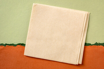 blank napkin against abstract paper landscape in green and orange tones