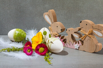 Family of wooden Easter bunnies and Easter eggs with spring flowers.