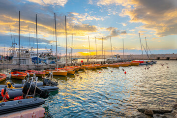 A colorful sunset sky above the boats moored at the Jaffa port Harbor, the oldest seaport in the...